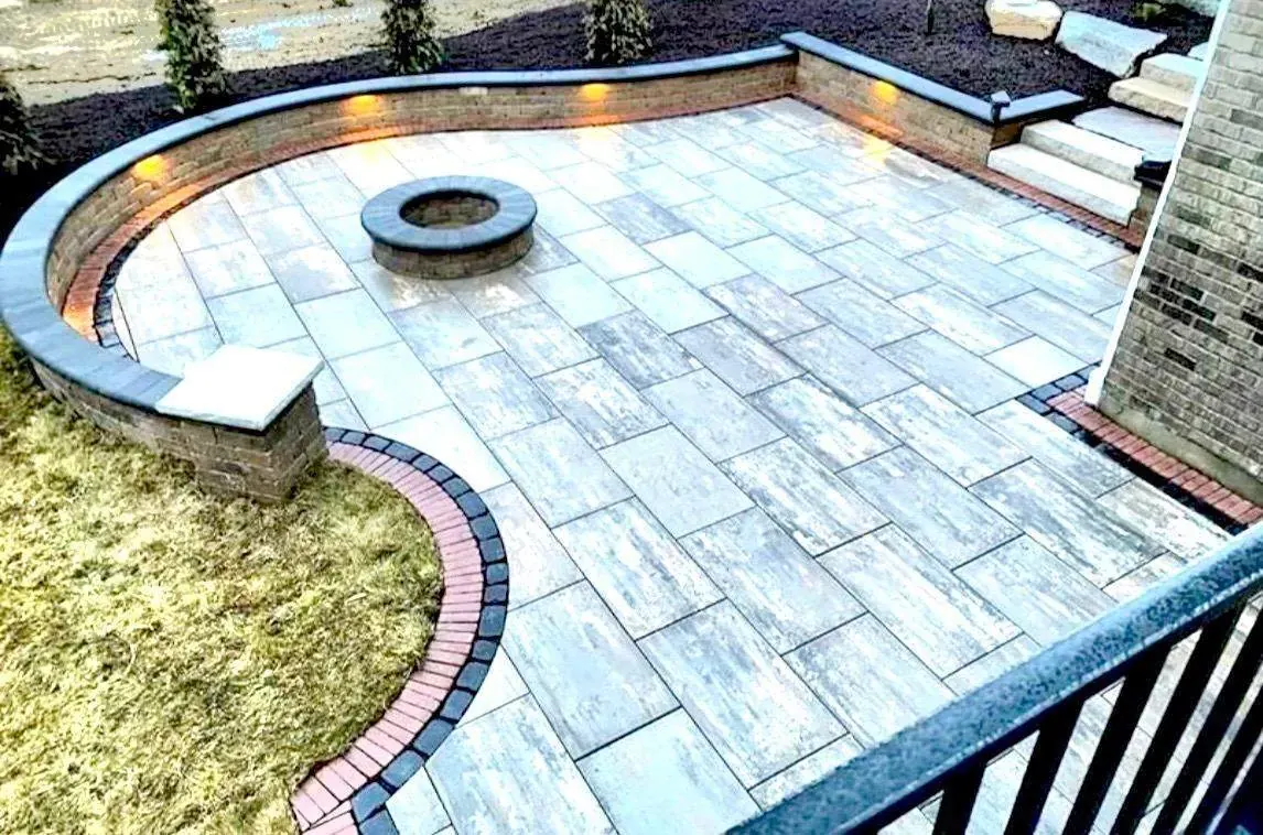 Paver patio with a lit seat wall and fire pit