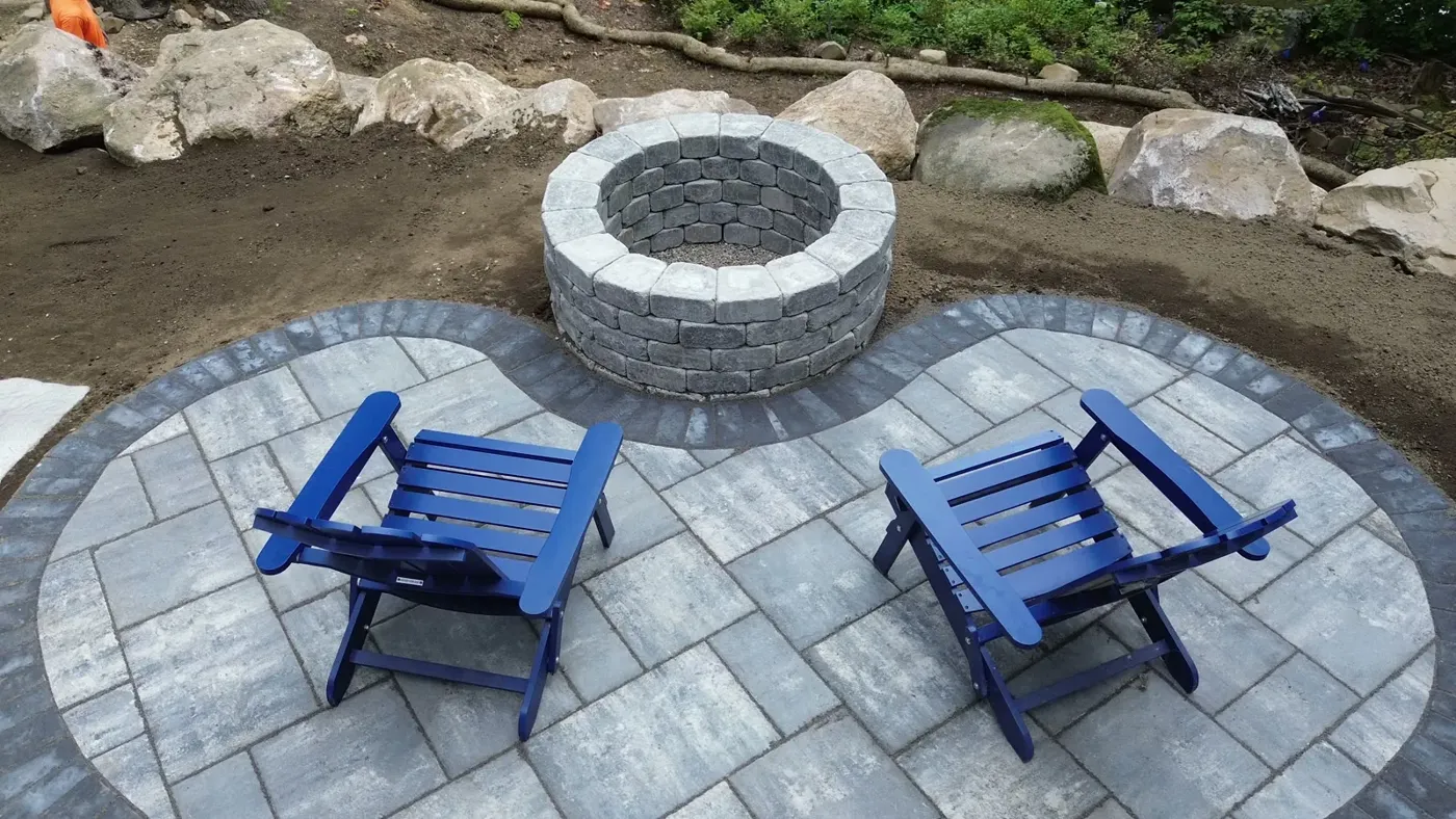Round paver patio built around a stone fire pit